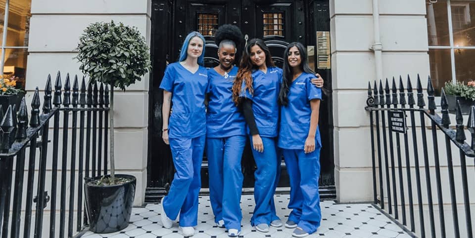 Sofwave ultrasound skin lifting Amsterdam - four nurses in blue scrubs outside a Georgian Four nurses in blue scrubs outside a Georgian clinic entrance, Sofwave ultrasound skin lifting Amsterdam